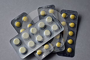 A bunch of white and yellow tablets in blisters on a white background