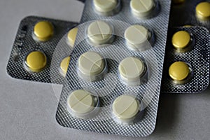 A bunch of white and yellow tablets in blisters on a white background