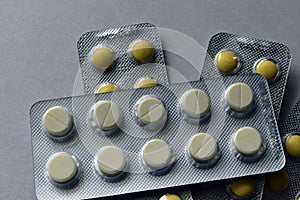 A bunch of white and yellow tablets in blisters on a white background