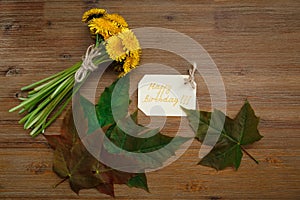 Bunch of Yellow Dandelions,Birthday Wish Card,Green Leaves.Autumn Garden's Background.Wooden Table