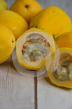 Bunch of yellow or golden passion fruit, whole and cut, on timber background