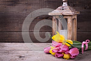 Bunch yellow and pink spring tulips and candle in lantern on v