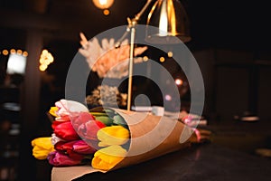 Bunch of Yellow red white  bouquet of tulips laying in nightclub restaurant. Fresh spring Greeting card for Saint Valentine`s