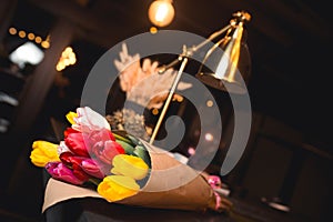 Bunch of Yellow red white  bouquet of tulips laying in nightclub restaurant. Fresh spring Greeting card for Saint Valentine`s