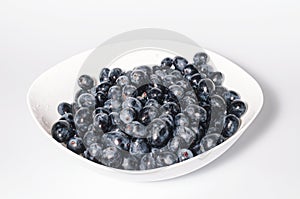 Bunches of blue grapes in white plate on white background. Berries, summer harvest, healthy eating