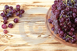 Bunches of fresh ripe pink grapes in wicker basket on piece of sackcloth on a wooden textured backdrop. Beautiful background with