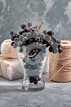 Bunches of fresh ripe red grapes on a concrete textural surface. Branch of pink grapes. Red wine grapes. dark grapes