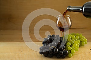 Bunches of grapes and a glass of wine on a wooden background