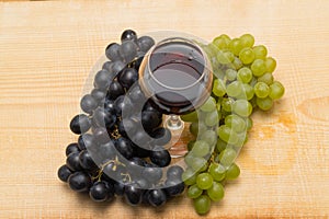 Bunches of grapes and a glass of wine on a wooden background