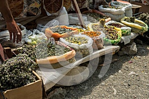 Bunches of healing dried herbs, sour lavash and mortar for sale.