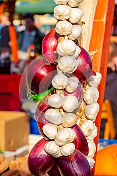 Bunches of red onions and garlic hanging on a rope for sale in the food market