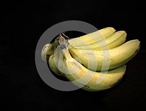 a bundle of bananas sitting on a table with a black background