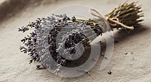 A bundle of dried lavender (Lavandula) tied with twine rests on a textured textile surface. The