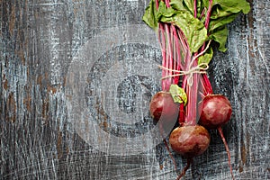 Bundle of fresh organic farmer young beetroots on dark scratched background, close-up, top view