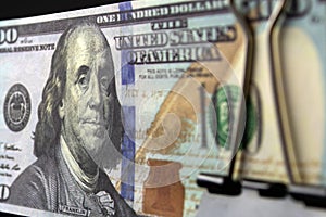 A bundle of hundred-dollar bills compressed by a binder