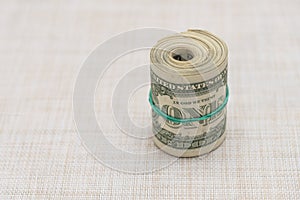 A bundle of money twisted into a bundle and tied with a green rubber band