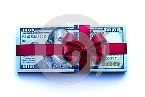 A bundle of one hundred dollar bills tied with a red ribbon