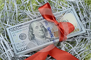 A bundle of one hundred dollar bills tied up with a red ribbon