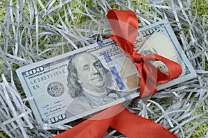 A bundle of one hundred dollar bills tied up with a red ribbon