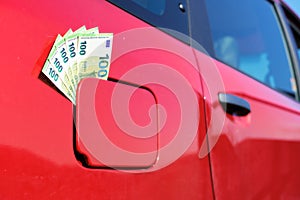 bundle of one hundred euro banknotes in the fuel tank cap of a car