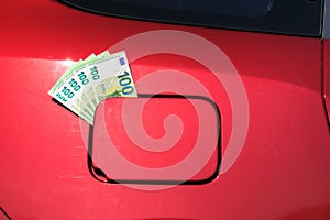 Bundle of one hundred euro notes sticking out of a fuel tank lid