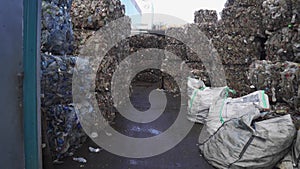 Bundle of pressed plastic bottles prepared for a garbage recycling on waste recycling plant. Camera moves to the side