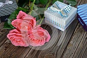 Bundle of roses and gifts on table
