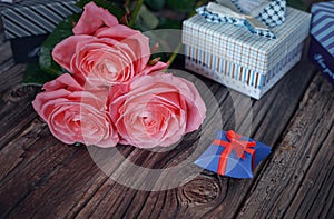 Bundle of roses and gifts on table