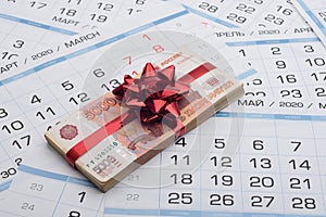 A bundle of Russian five-thousandth bills with a red bow lies on a background from a calendar