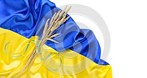 Bundle of wheat spikes with yellow and blue ribbon on the background of the flag of Ukraine isolated on white. Harvest of wheat