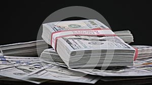 Bundles of Dollars Lying on a Pile of Money and Rotate on Black Background