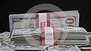 Bundles of Dollars Lying on a Pile of Money and Rotate on Black Background