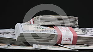 Bundles of Dollars Lying on a Pile of Money and Rotate on Black Background