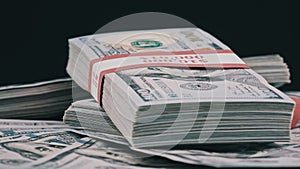 Bundles of Dollars Lying on a Pile of Money and Rotate on Black Background