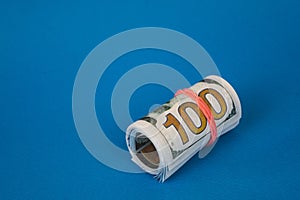 bundles of twisted money of different currencies on a blue background