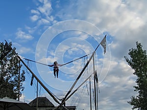 Bungee jumping at a carnival with girl up high against a cloudy sky