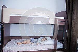 Bunk bed in child room. little girl alone lying on bed. chocolate shade in the interior with white walls