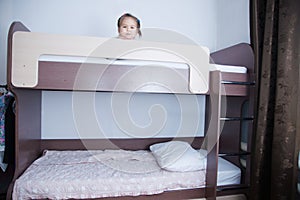 Bunk bed in child room. little girl alone lying on bed. chocolate shade in the interior with white walls