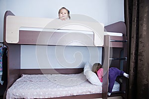 Bunk bed in child room.two little girl playing on bed. chocolate shade in the interior with white walls