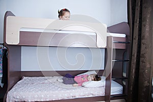 Bunk bed in child room.two little girl playing on bed. chocolate shade in the interior with white walls