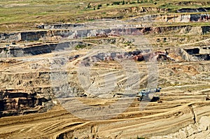 Bunk wall surface mine with exposed colored minerals and brown coal, the pit mining equipment