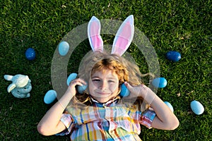 Bunny boy hunting eggs in park, Funny little Easter bunny child hunt easter egg. Easter kids portrait outdoor. Top view