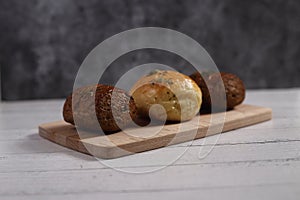 Buns of bread on cutting board isolated on white wooden background