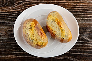 Buns with cheese and garlic in plate on wooden table. Top view