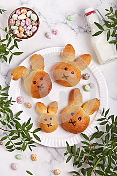 Buns made from yeast dough in a shape of Easter bunny, and colored candy eggs