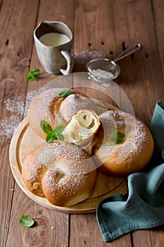 Buns with powdered sugar and milk on a wooden table