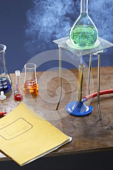 Bunsen burner heating flask with science equipment in laboratory