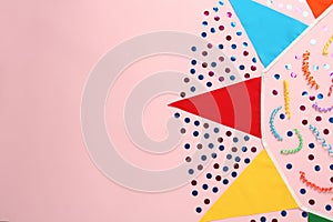 Bunting with colorful triangular flags and other festive decor on pink background, flat lay. Space for text