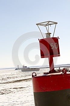 Buoy with The Crib and lighthouses on pier along shipping channel on frozen Lake Superior in Duluth, Minnesota