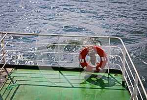 Buoy or lifebuoy ring on shipboard in evening sea. Flotation device on ship side on seascape. Safety, rescue, life preserver.